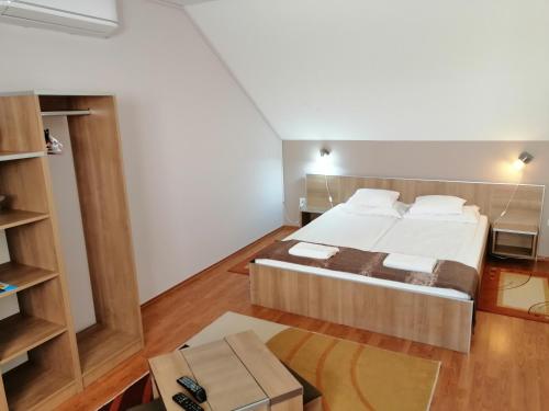 um quarto com uma cama grande e uma caixa em Csipkeház Apartman em Cserkeszőlő