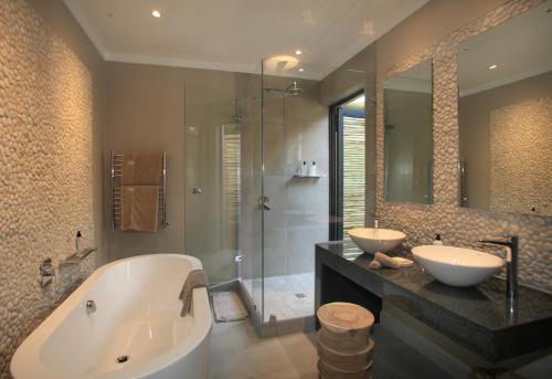 La salle de bains est pourvue de 2 lavabos, d'une baignoire et d'une douche. dans l'établissement Scallop Lodge, à Plettenberg Bay