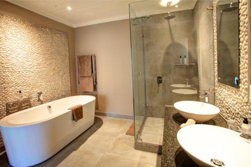 a bathroom with a tub and a sink and a shower at Scallop Lodge in Plettenberg Bay