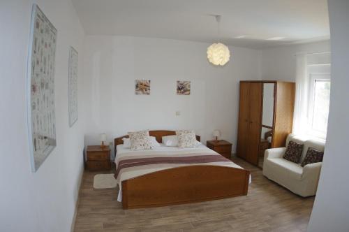 a white bedroom with a bed and a chair at Apartment Mia in Vinkuran