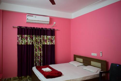 a bedroom with pink walls and a bed with a curtain at Jupiter Lodge in Siliguri