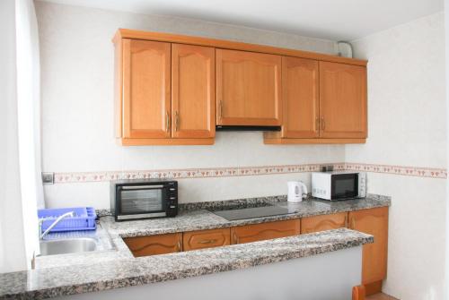 a kitchen with wooden cabinets and a microwave at APARTAMENTS COLELLS in Bordes d´Envalira