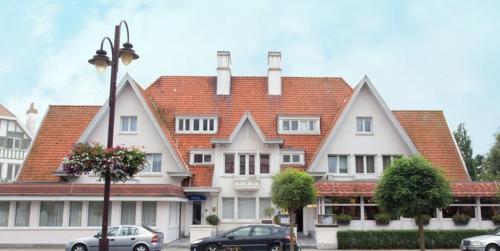 a large house with cars parked in front of it at Hotel Internos in De Haan