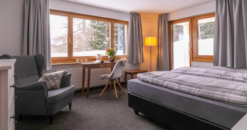a bedroom with a bed and a chair and a desk at Seeblick Davos in Davos