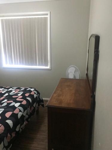 a bedroom with a bed and a dresser and a window at Grey Pebbles in Nowra