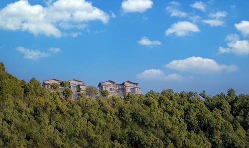 a building on top of a hill with trees at The Manor Luxury Apartments, Shimla in Mashobra