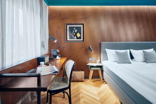 a bedroom with a bed and a desk with a chair at art Hotel Tucholsky in Bochum