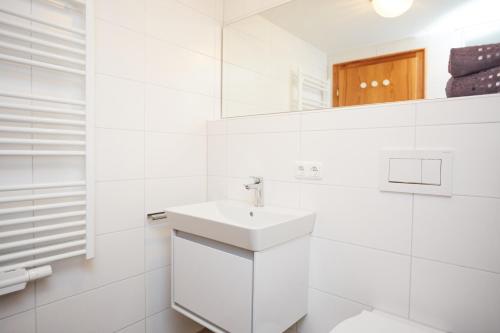 a white bathroom with a sink and a mirror at Ferienwohnung Bacco in Oberstdorf