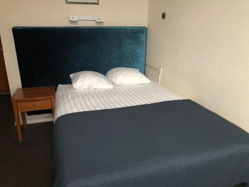 a bedroom with a bed with a blue headboard and a table at Hotel Wilhelmina in Venlo