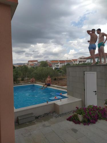 un groupe d'hommes se tenant au bord d'une piscine dans l'établissement Apartment Juric, à Trogir