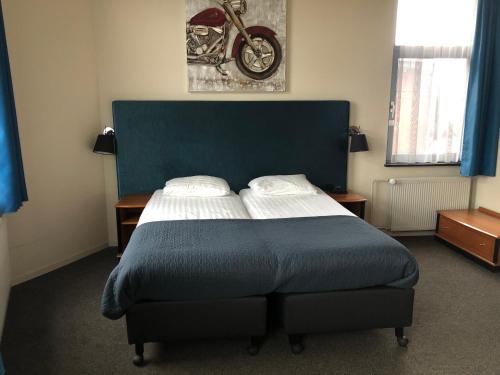 a bedroom with a bed with a blue head board at Hotel Wilhelmina in Venlo
