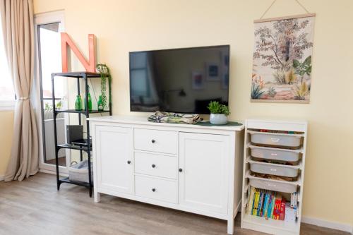 a living room with a tv and a white dresser at Apartments Braunschweig - Noahs Home - Balkon - Küche - Parkplatz in Braunschweig
