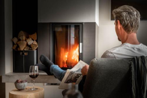 a man sitting in a chair in front of a fireplace at Sporthotel Chalet in Gaschurn