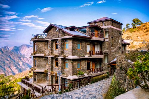 a large stone building on the side of a mountain at The Manor Luxury Apartments, Shimla in Nāldera