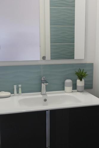 une salle de bain avec un lavabo blanc et un miroir dans l'établissement LE COIN COSY avec Balcon Terrasse parking privé et linge de lit compris, à Sarlat-la-Canéda