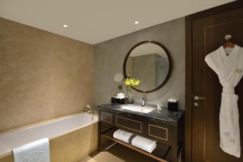 a bathroom with a sink and a tub and a mirror at Taj Skyline Ahmedabad in Ahmedabad