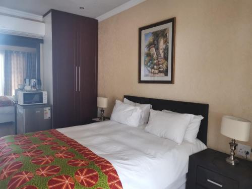1 dormitorio con 1 cama blanca grande con manta roja y verde en Aquila Guest House, en Pretoria