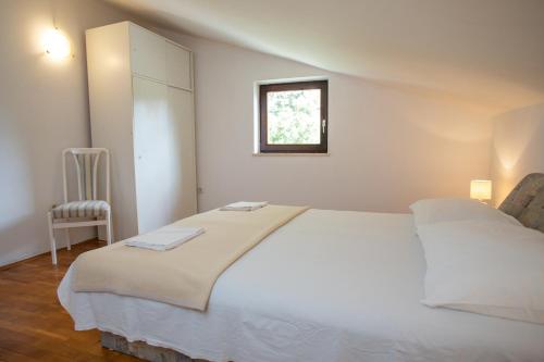 a bedroom with a white bed and a window at House Emilija in Novalja