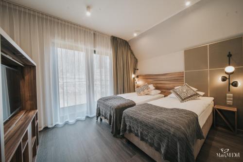 a hotel room with two beds and a large window at Lake Hill Karkonosze Apartments in Sosnówka