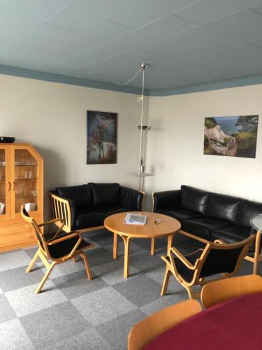 a living room with a black couch and a table at Feriecentret Østersø Færgegård in Kalvehave