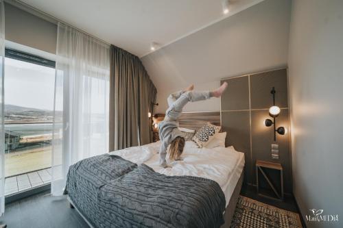 a person jumping on a bed in a hotel room at Lake Hill Karkonosze Apartments in Sosnówka