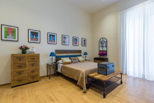 a bedroom with a bed and a dresser and a window at La Gatta Cenerentola Rooms in Naples