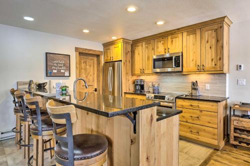 a kitchen with wooden cabinets and a counter with bar stools at Frisco Home with Mountain Views Walk to Main St! in Frisco