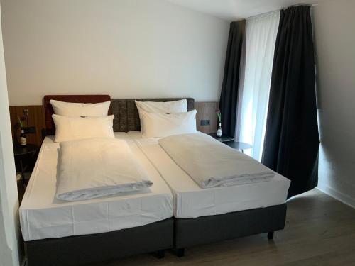 ein Bett mit weißer Bettwäsche und Kissen in einem Schlafzimmer in der Unterkunft Altstadthotel Arte in Fulda