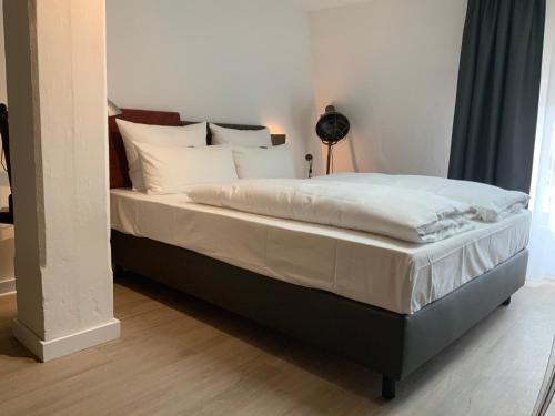 a bed with white sheets and pillows in a bedroom at Altstadthotel Arte in Fulda