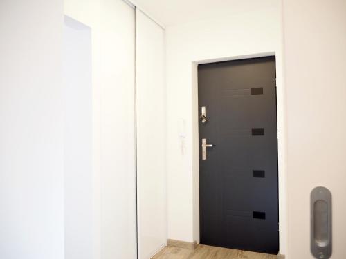a black door in a white room with a mirror at Telimeny in Kraków