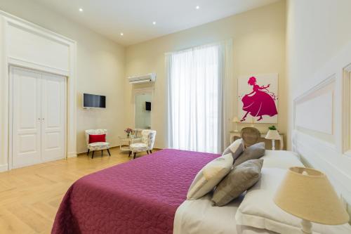 a bedroom with a large bed with a purple blanket at La Gatta Cenerentola Rooms in Naples
