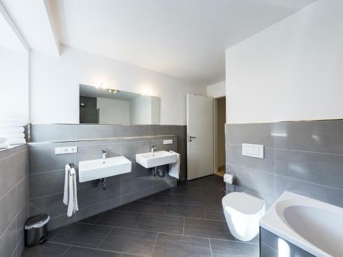 ein Badezimmer mit zwei Waschbecken, einem WC und einem Spiegel in der Unterkunft GardenLodge in Garmisch-Partenkirchen