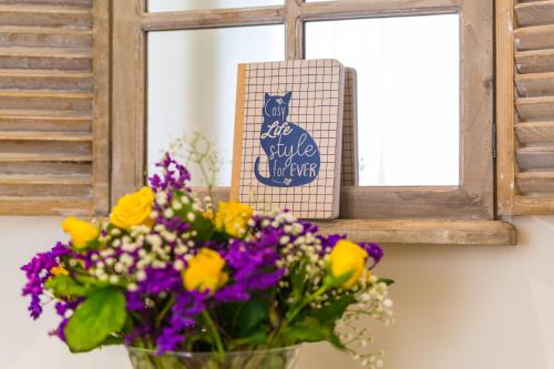 a vase of flowers next to a window with a sign at La Gatta Cenerentola Rooms in Naples