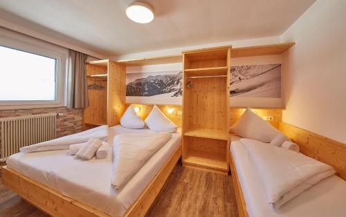 two beds in a room with wooden walls at Ski & Bike Appartements Forsthaus in Saalbach Hinterglemm