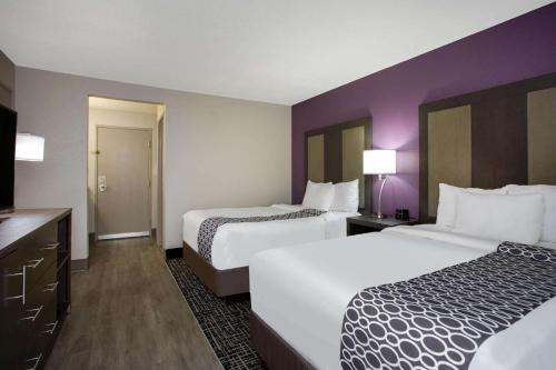 two beds in a hotel room with purple walls at La Quinta Inn by Wyndham Roanoke Salem in Salem