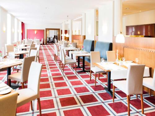 a restaurant with tables and chairs in a room at Novotel Hildesheim in Hildesheim