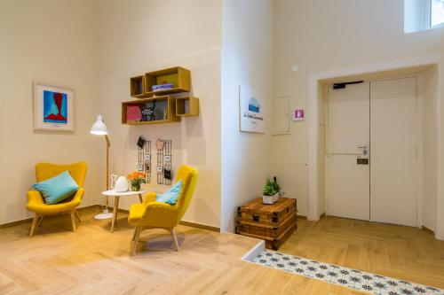 a living room with two yellow chairs and a table at La Gatta Cenerentola Rooms in Naples