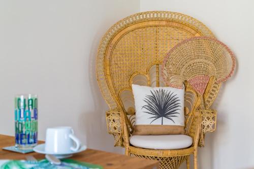 a rattan chair with a pillow with a palm tree on it at La Gatta Cenerentola Rooms in Naples