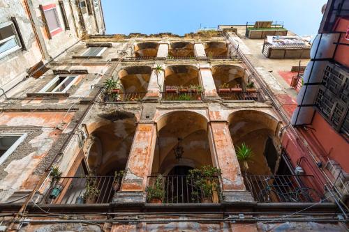 an old building with windows and balconies with plants at La Gatta Cenerentola Rooms in Naples
