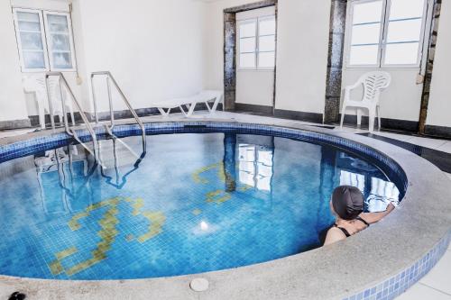 a woman is sitting in an indoor swimming pool at Balneario Hotel Dávila in Caldas de Reis