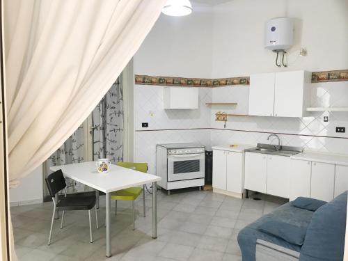 a white kitchen with a table and a table and chairs at Home La Corte in SantʼAntimo