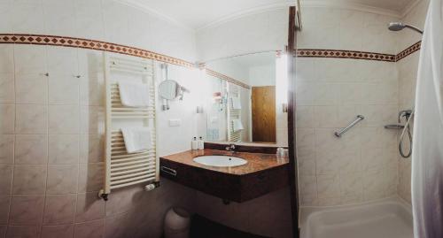 a bathroom with a sink and a shower and a tub at Burghotel Pass in Südlohn