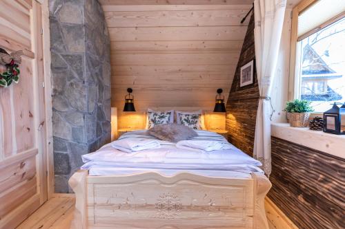 a bed in a room with a stone wall at TatryTop Osada Gazdówka z sauną in Kościelisko