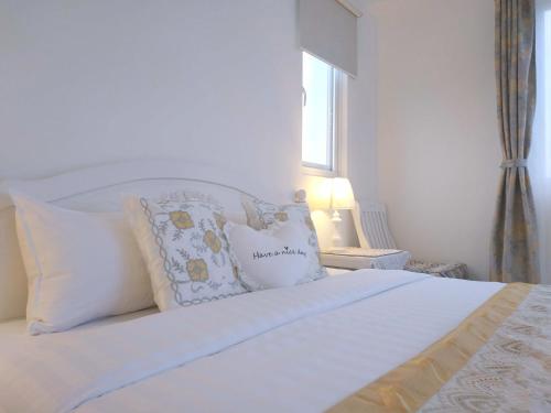 a bedroom with a white bed with pillows and a window at 後山，我的家 in Fenglin