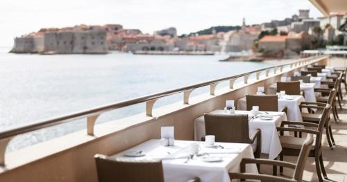 a row of tables and chairs on a balcony overlooking the water at Hotel Excelsior in Dubrovnik