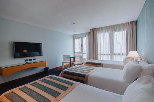 a hotel room with two beds and a flat screen tv at Hotel Spa Republica in Mar del Plata