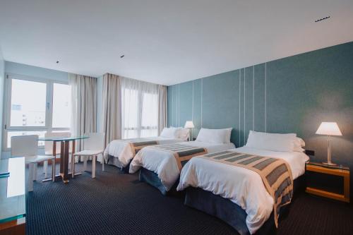 a hotel room with two beds and a table at Hotel Spa Republica in Mar del Plata
