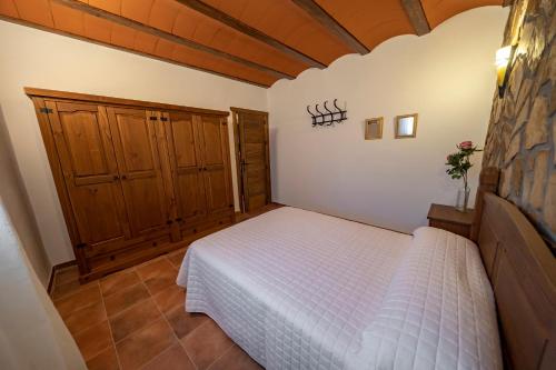 a bedroom with a white bed and wooden cabinets at Casa Rural Casa Las Flores in Tíjola