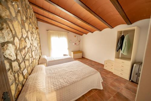 a bedroom with two beds and a stone wall at Casa Rural Casa Las Flores in Tíjola