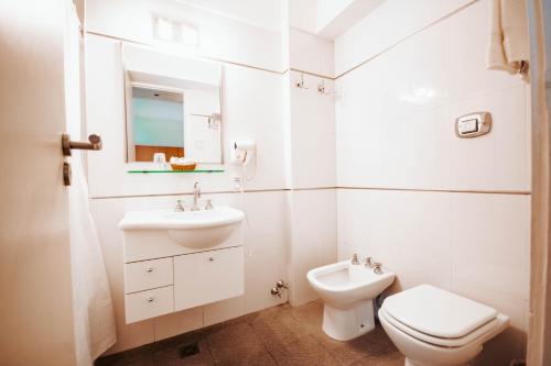 a white bathroom with a toilet and a sink at Hotel Spa Republica in Mar del Plata